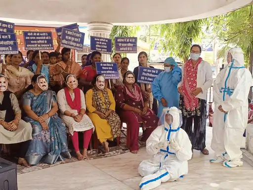 बिलासपुर में एनएचएम कर्मचारियों का अनोखा प्रदर्शन: मंत्रियों का मुखौटा पहनकर जताया विरोध